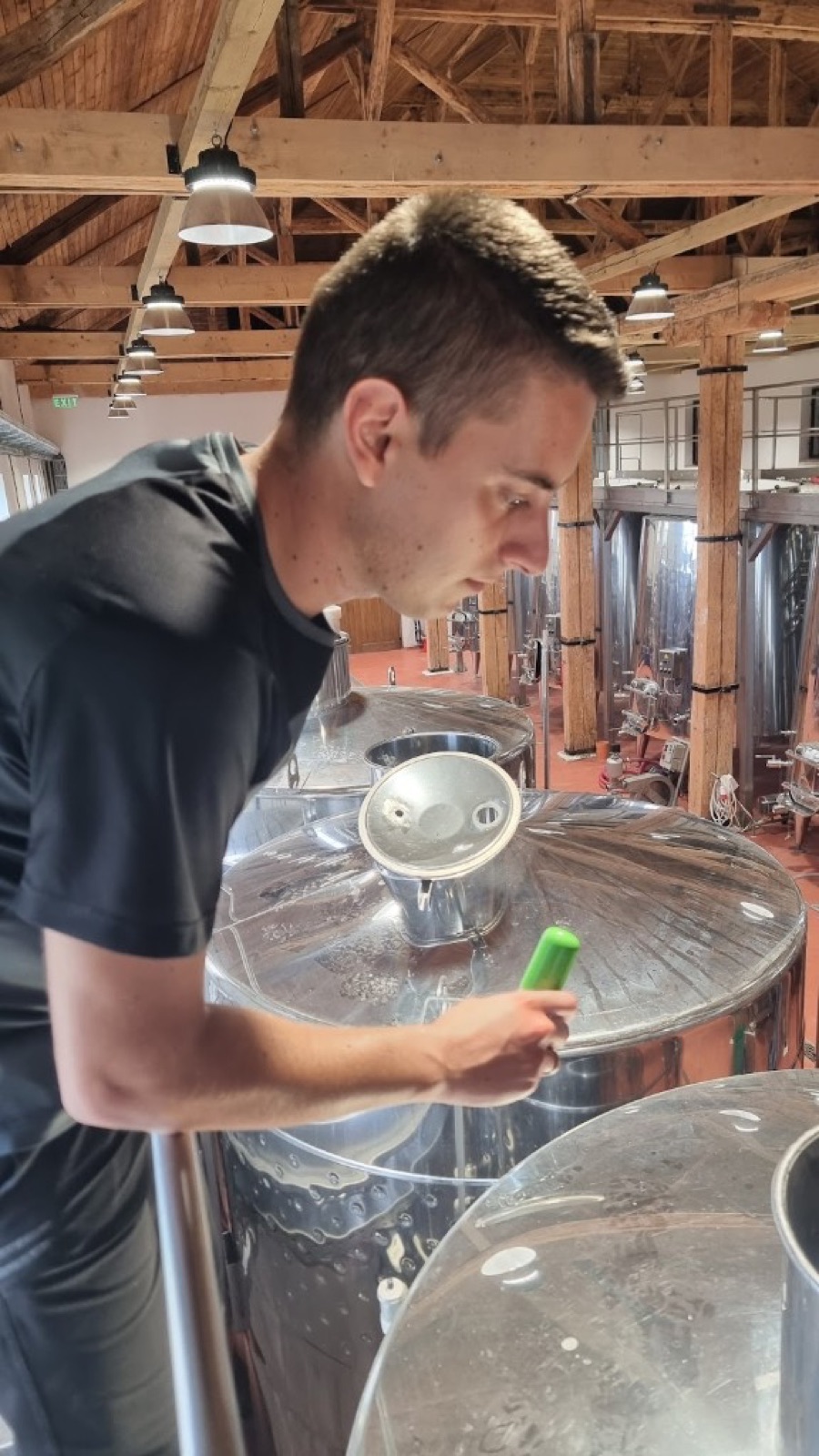 Winemaker lowering the green SCEPTER measuring float into an open stainless steel fermentation tank