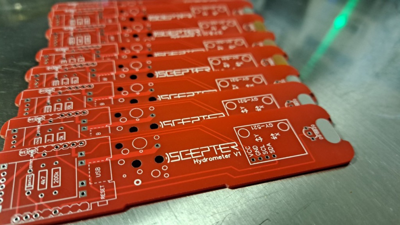 Freshly fabricated red SCEPTER Hydrometer V1 circuit boards stacked on a steel workbench