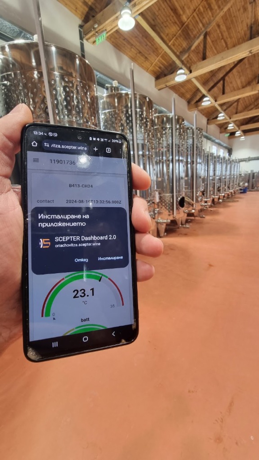 Phone in a winery tank hall showing the SCEPTER Dashboard 2.0 PWA install prompt