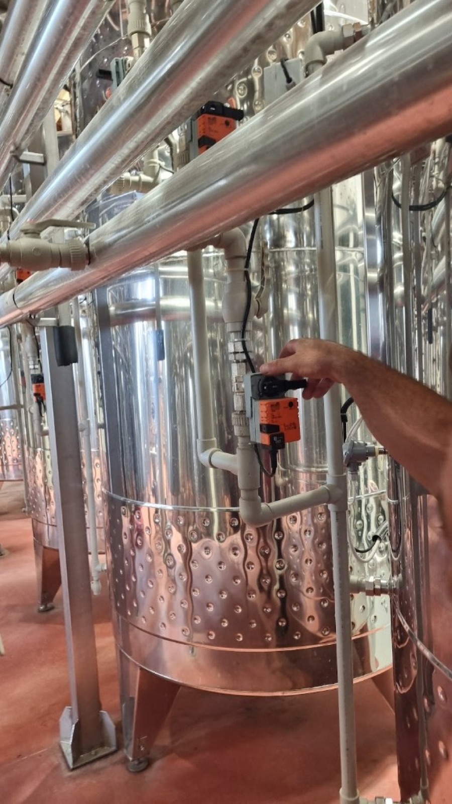 Belimo valve actuators mounted on cooling pipes between stainless steel wine tanks